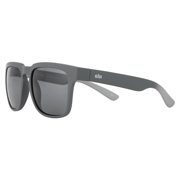 Gill 9744 Lumina solbrille på en båd, med strand i baggrunden